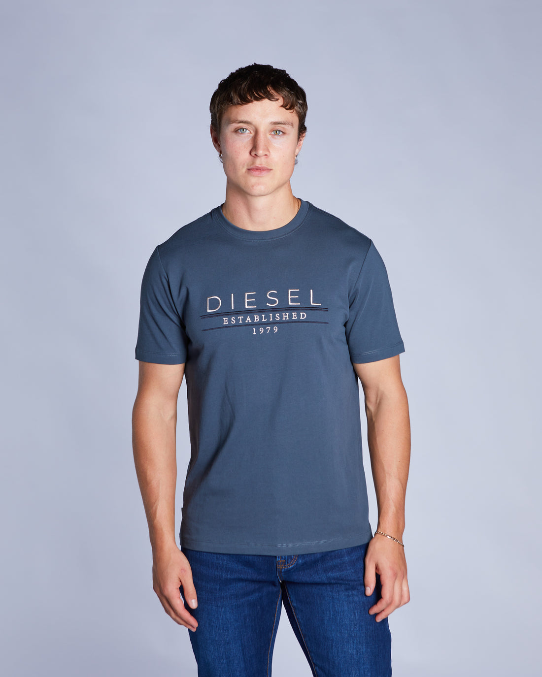 Man wearing a petrol blue tee and blue jeans