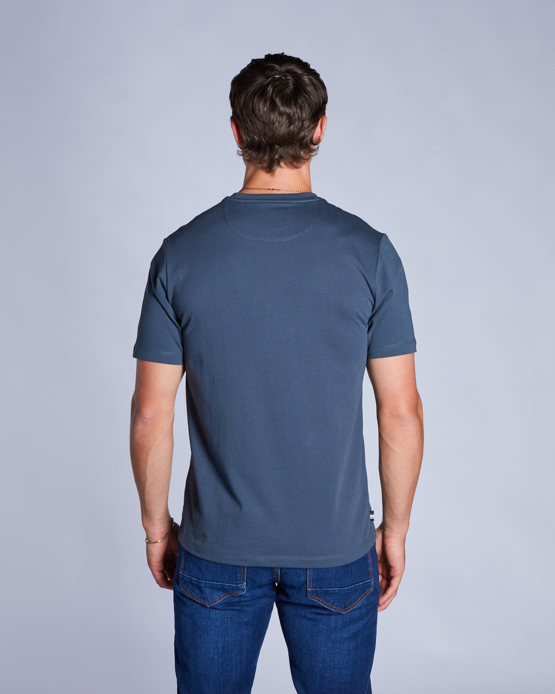 Man wearing a petrol blue tee and blue jeans-Back view