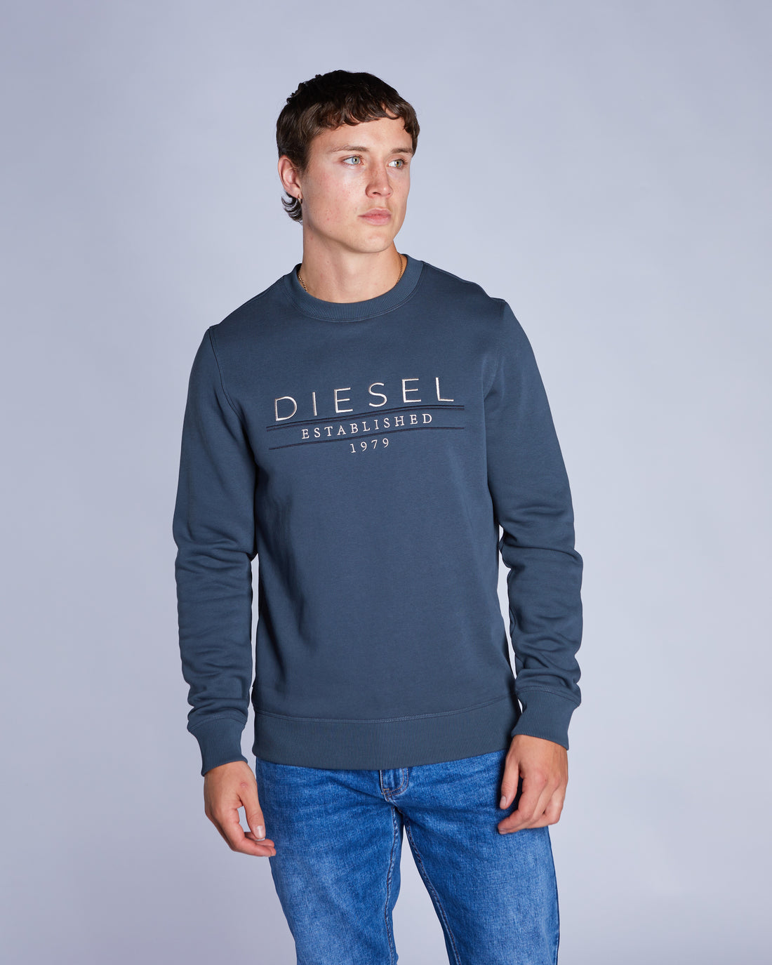 Man wearing a blue crew neck sweatshirt looking left