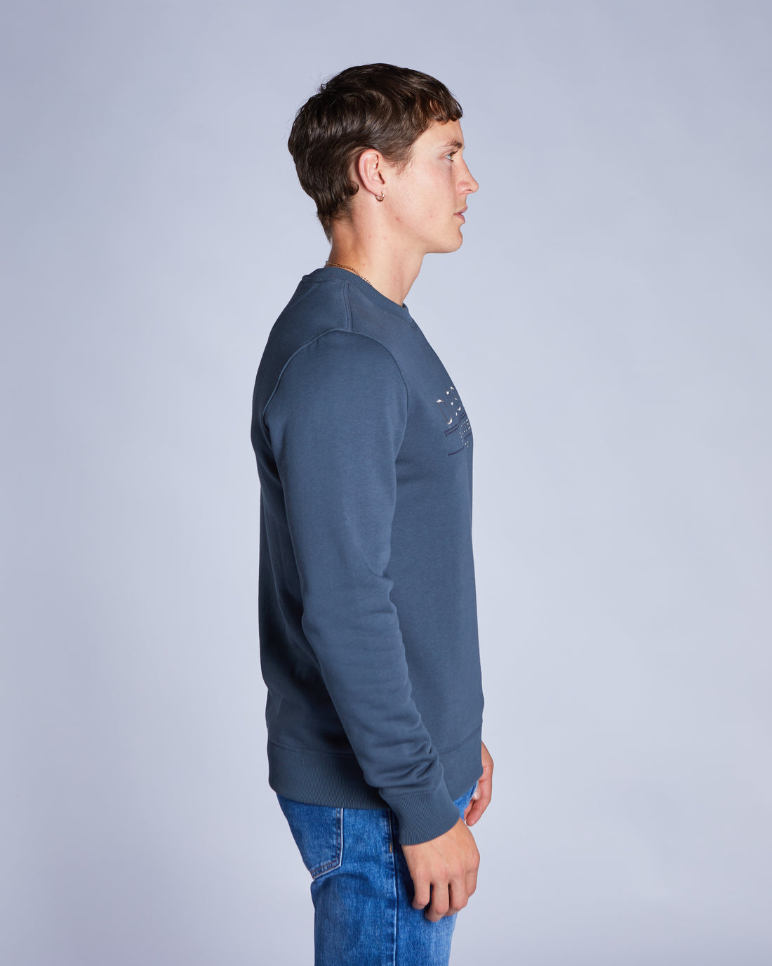 Man wearing a blue crew neck sweatshirt side view