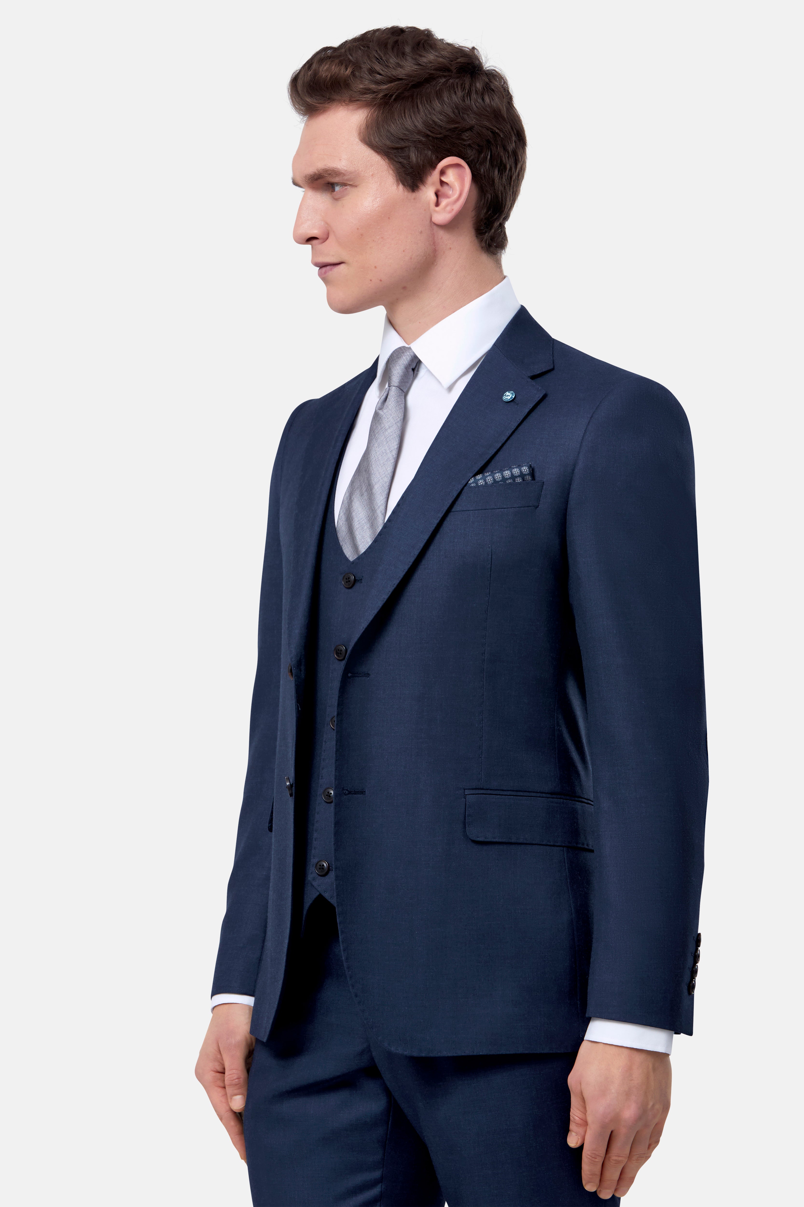 Man wearing a navy blue suit with a white shirt and gray tie on a white background