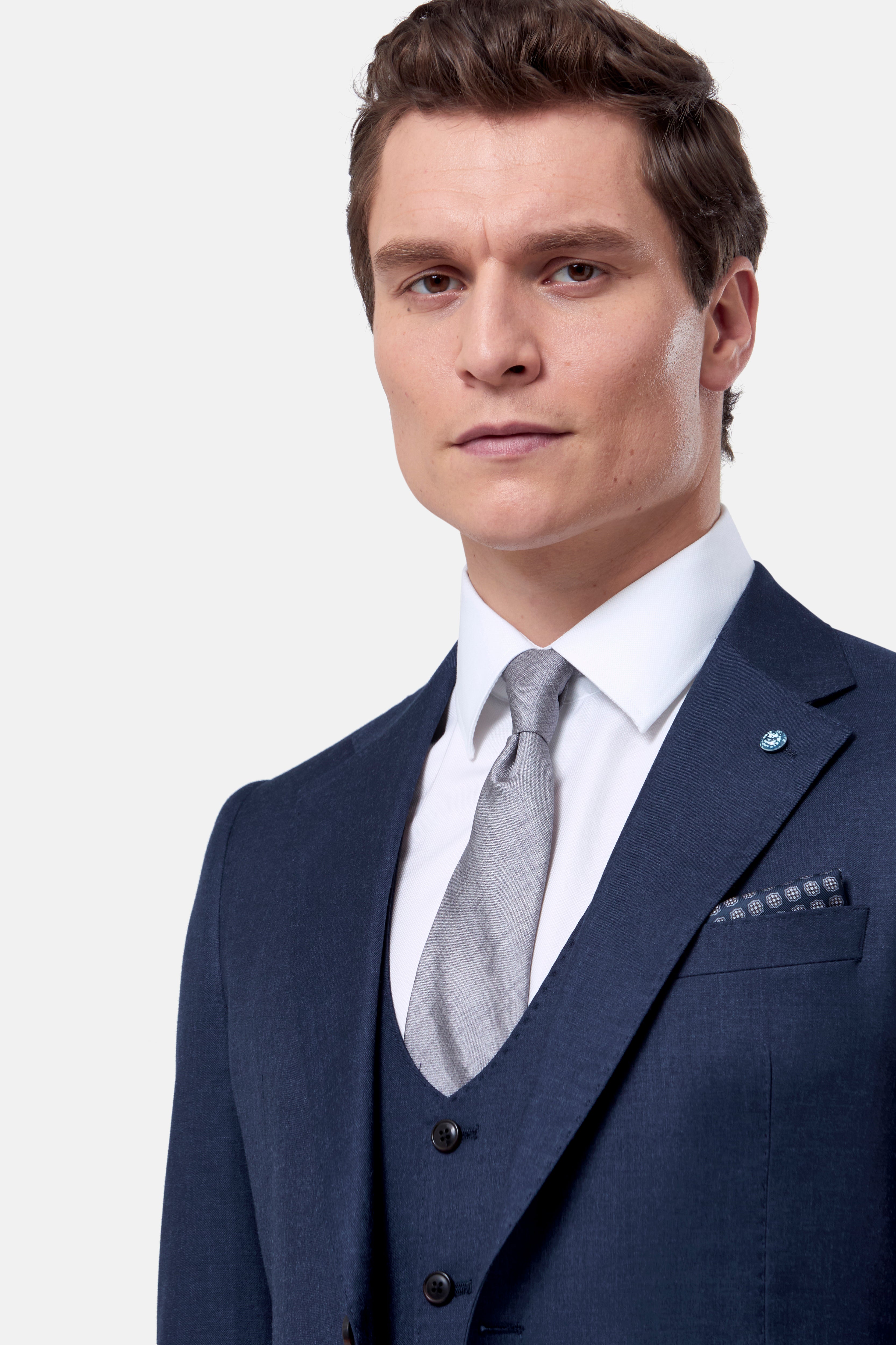 Man wearing a navy suit with a gray tie on a white background