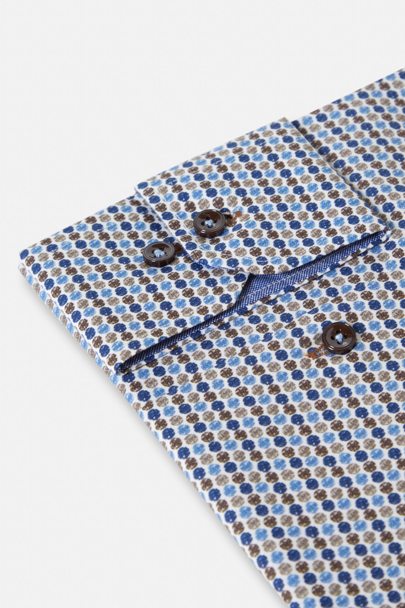 Close-up of a patterned fabric with blue and brown dots on a white background