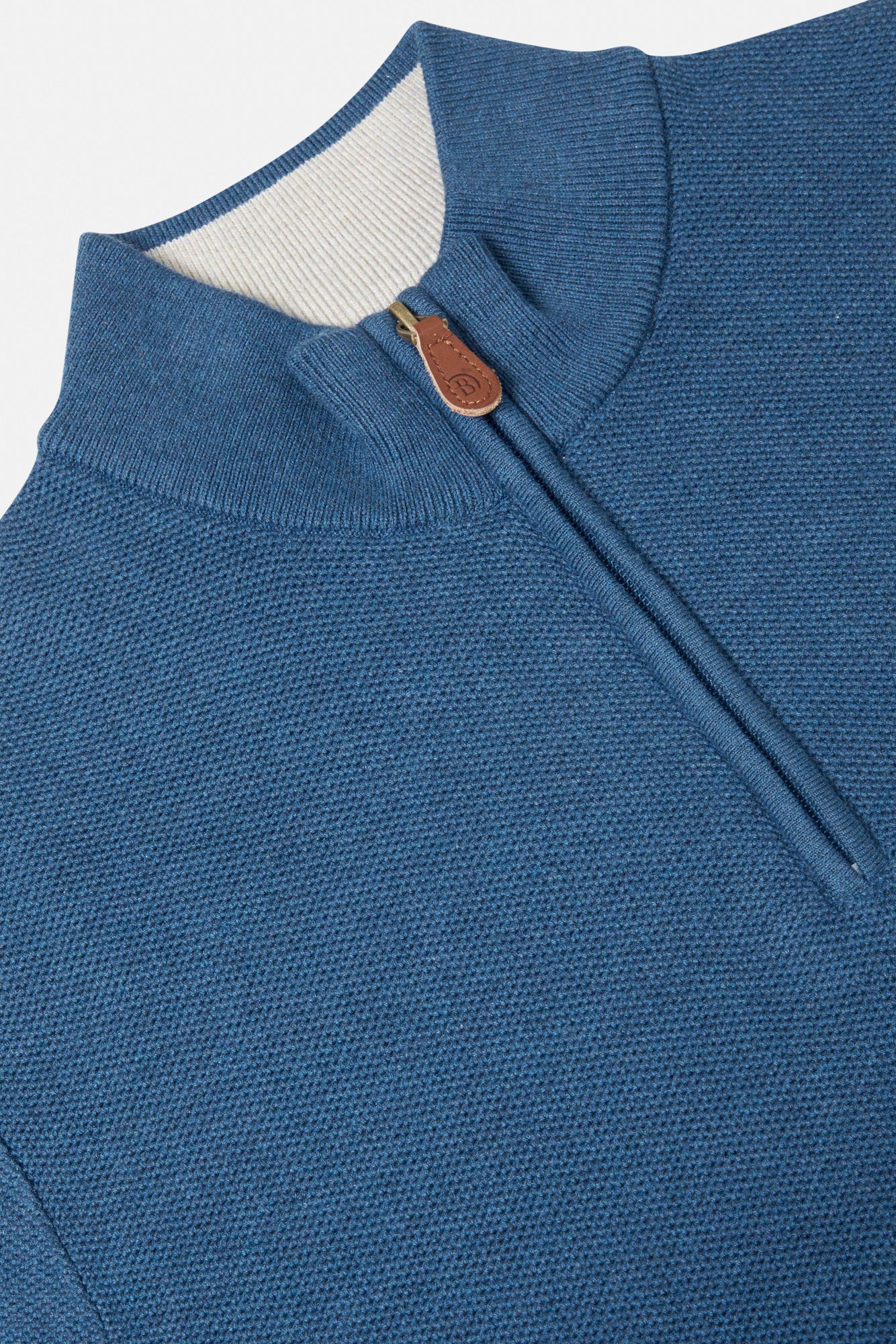 Close-up of a blue garment with a zipper and white lining on a light gray background