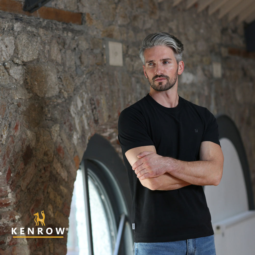 Man in a black t-shirt standing against a stone wall with 'KENROW' logo.