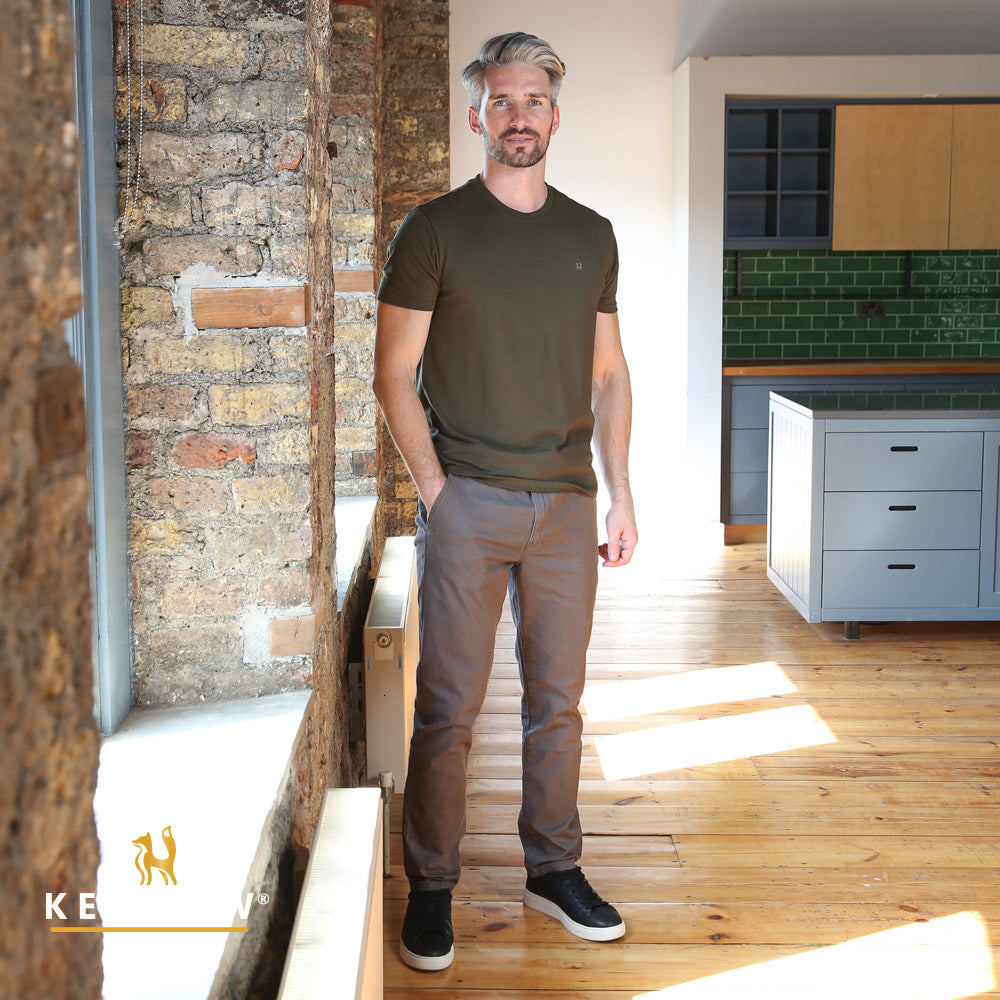 Man standing in a modern kitchen with wooden floors and brick walls.
