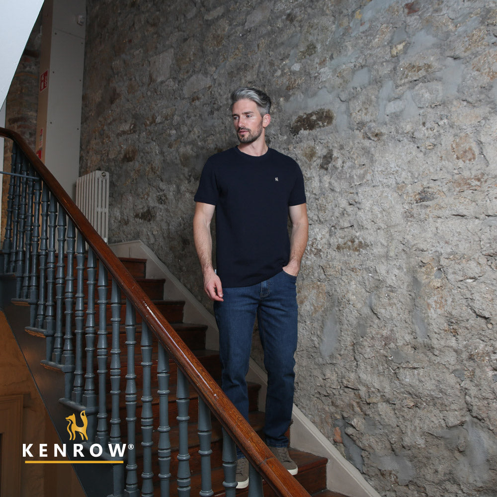 Man standing on a staircase with stone walls in the background, Kenrow logo visible