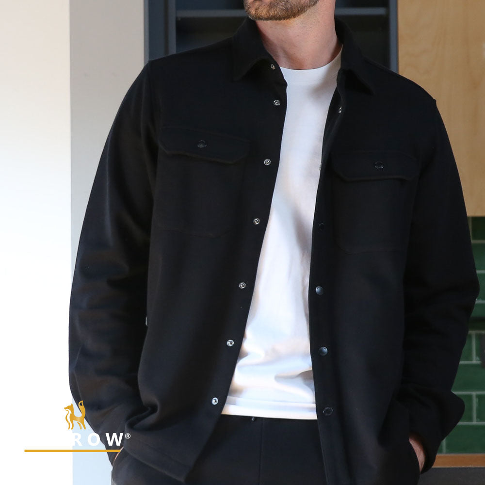 Person wearing a black jacket over a white shirt with a blurred background