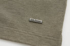 Rectangular metal 6th Sense logo badge on the lower hem of the brindle Evoke Polo.