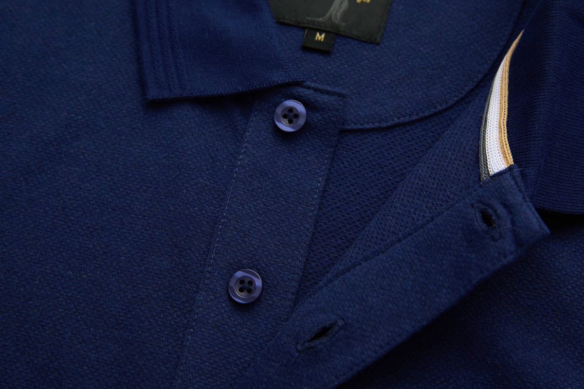Close-up of 6th Sense Evoke dress blue polo placket with two buttons and size M label