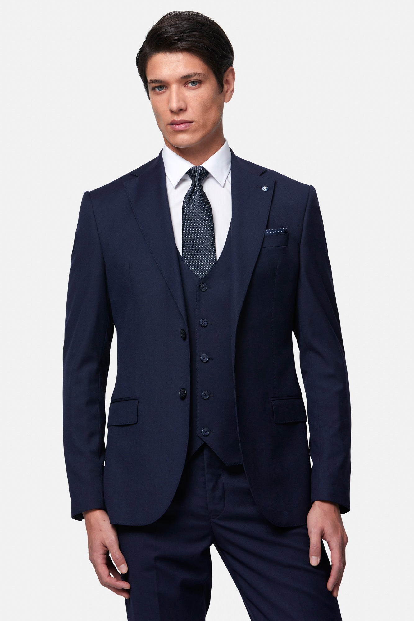 Man wearingthe Edina navy blue suit with a white shirt and tie on a light gray background