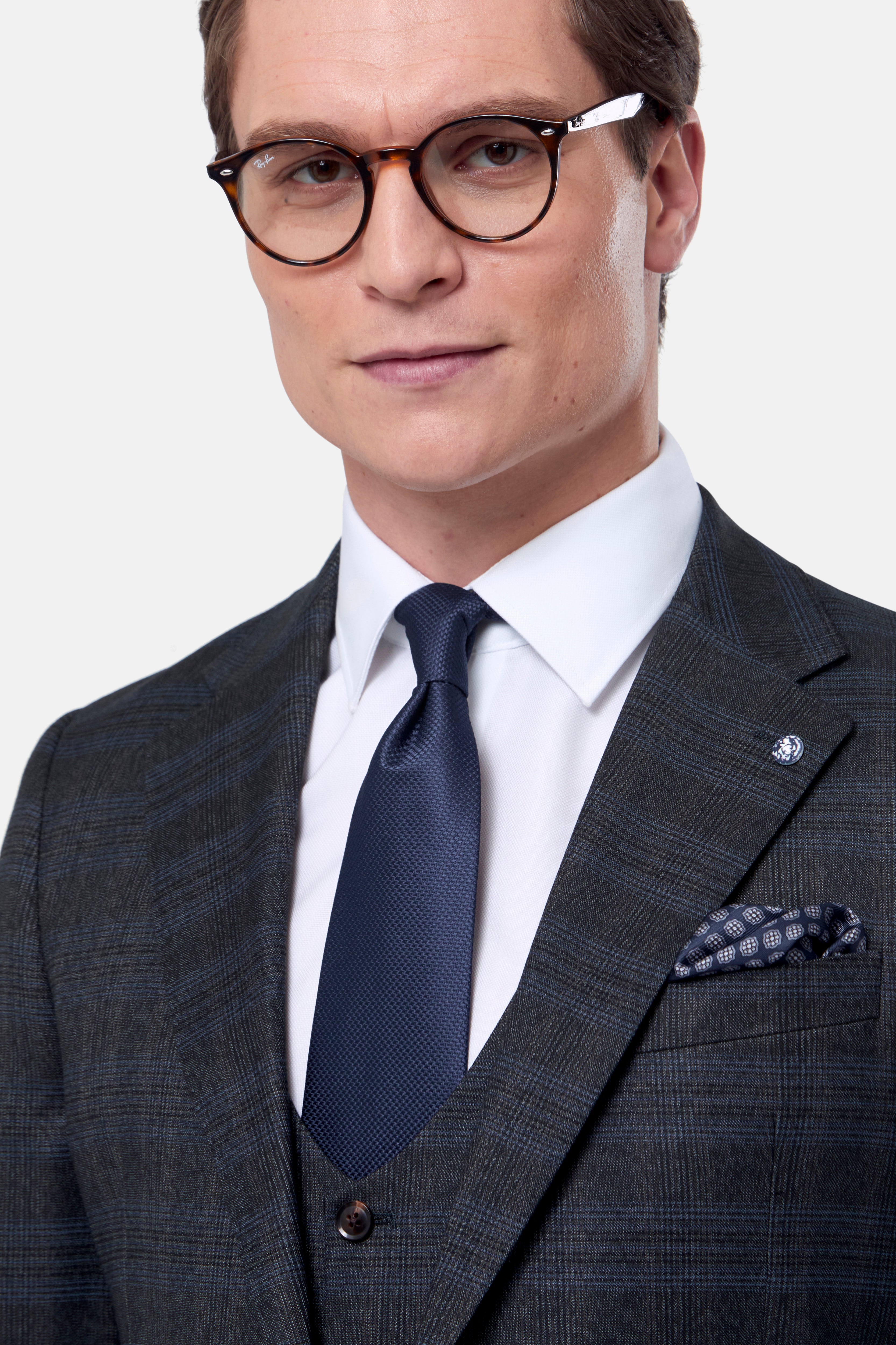 Man wearing a green suit with a navy tie and white shirt on a light gray background