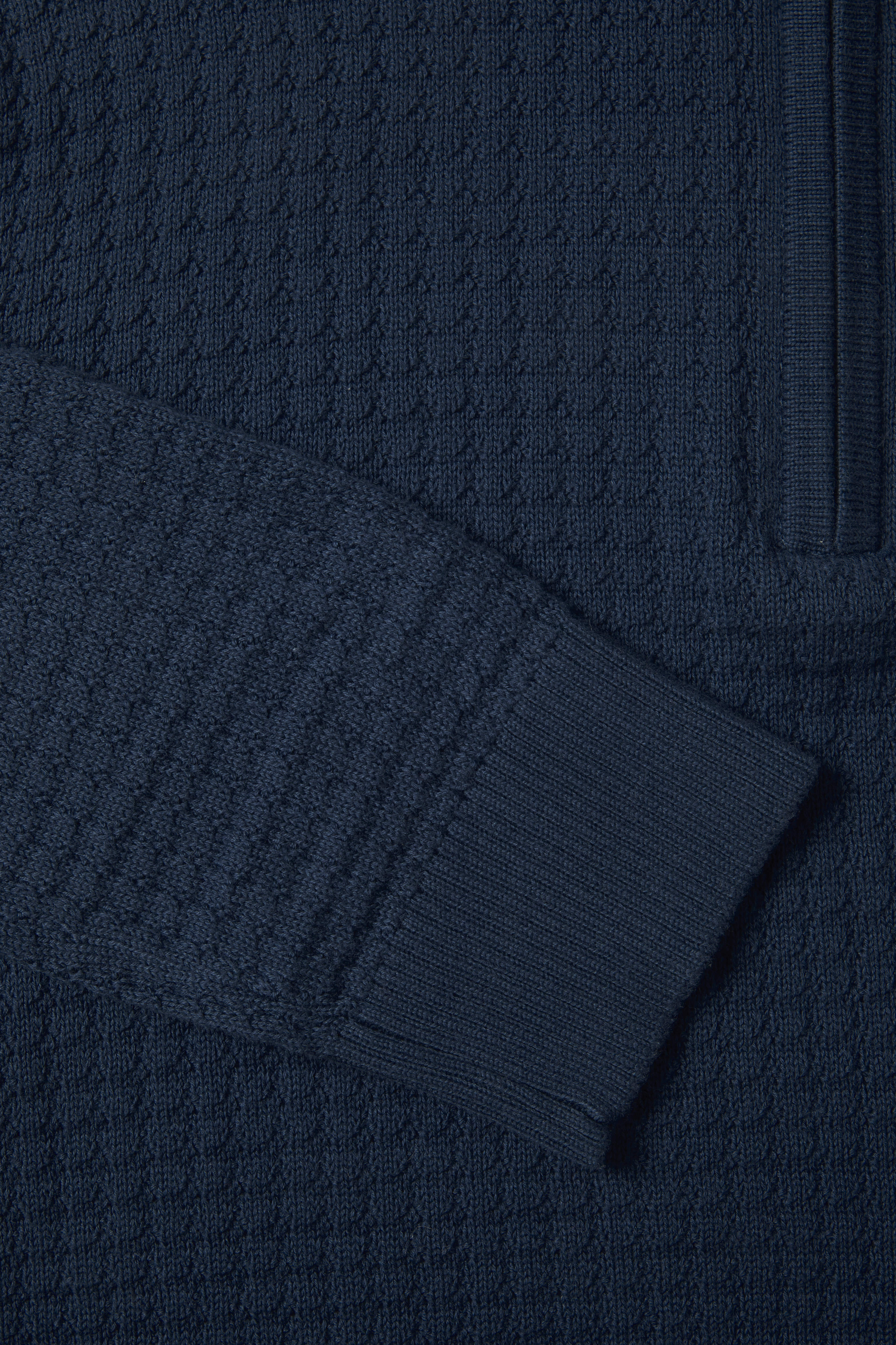 Close-up of a textured indigo blue fabric with a focus on the pattern and texture.