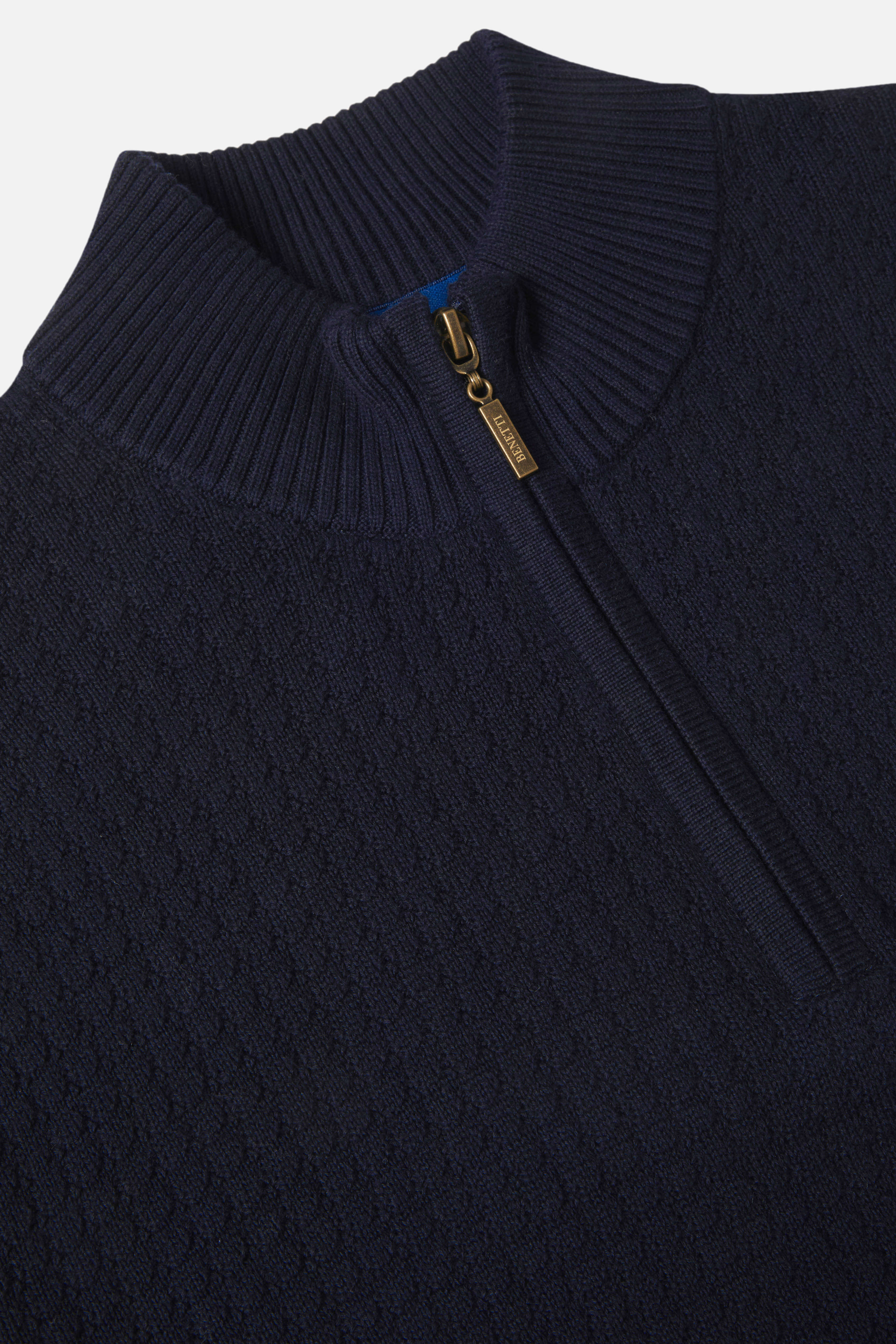 Close-up of a navy blue sweater with a zipper detail on a light gray background