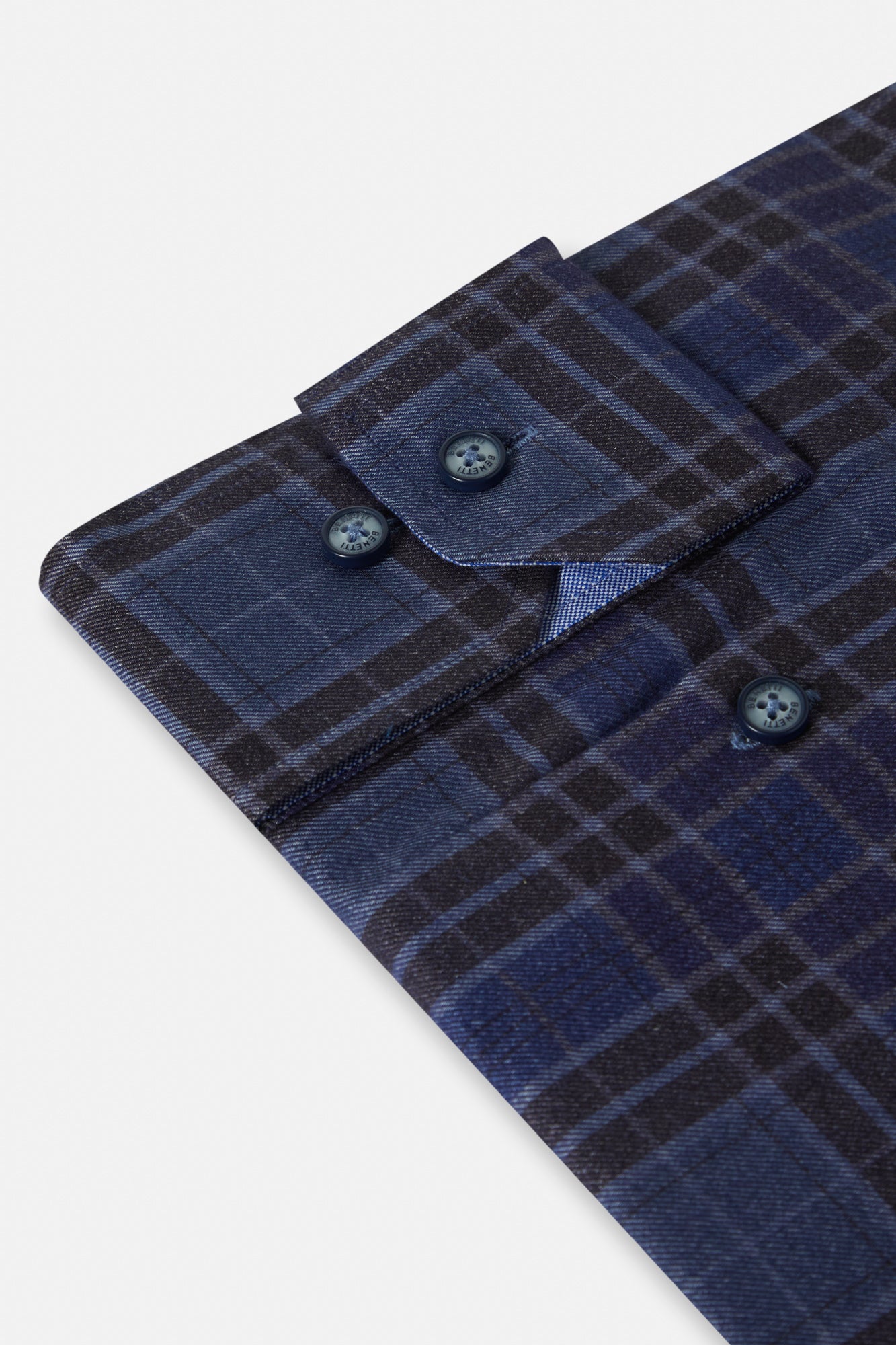 Close-up of a blue plaid shirt with buttons on a light gray background