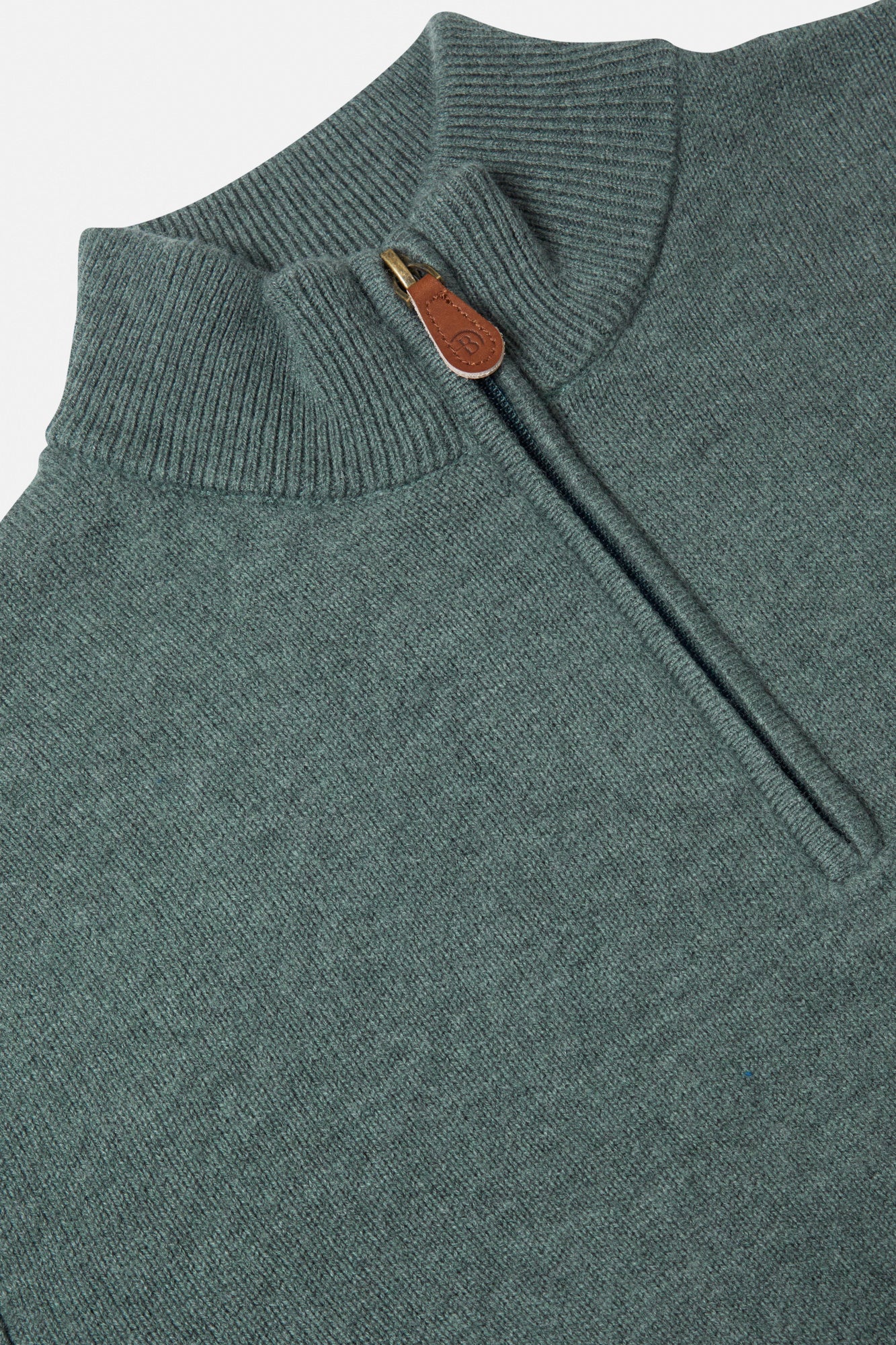 Green knit sweater with a zipper and wooden button on a light gray background