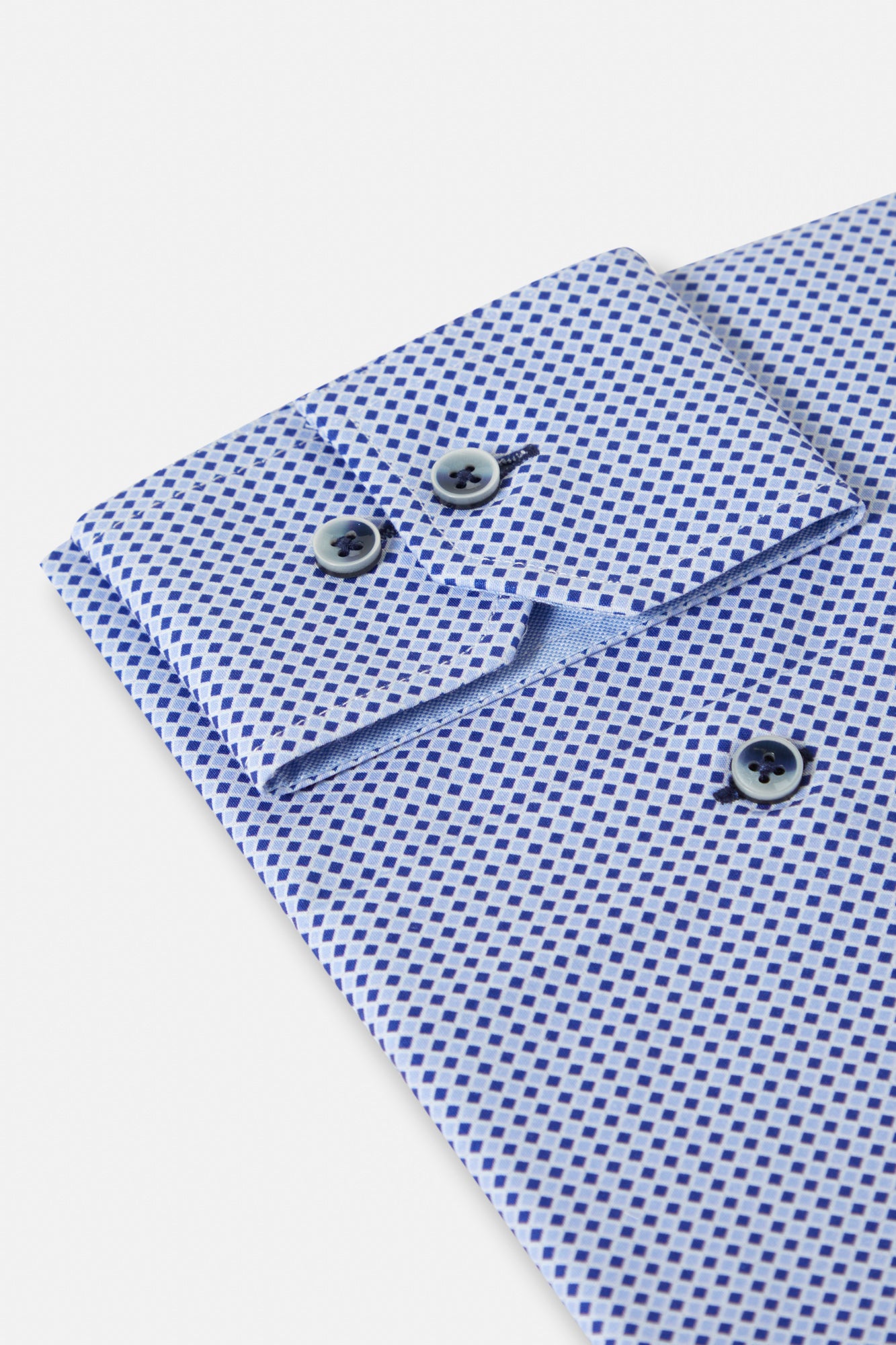 Close-up of a blue checkered shirt cuff with buttons on a light gray background