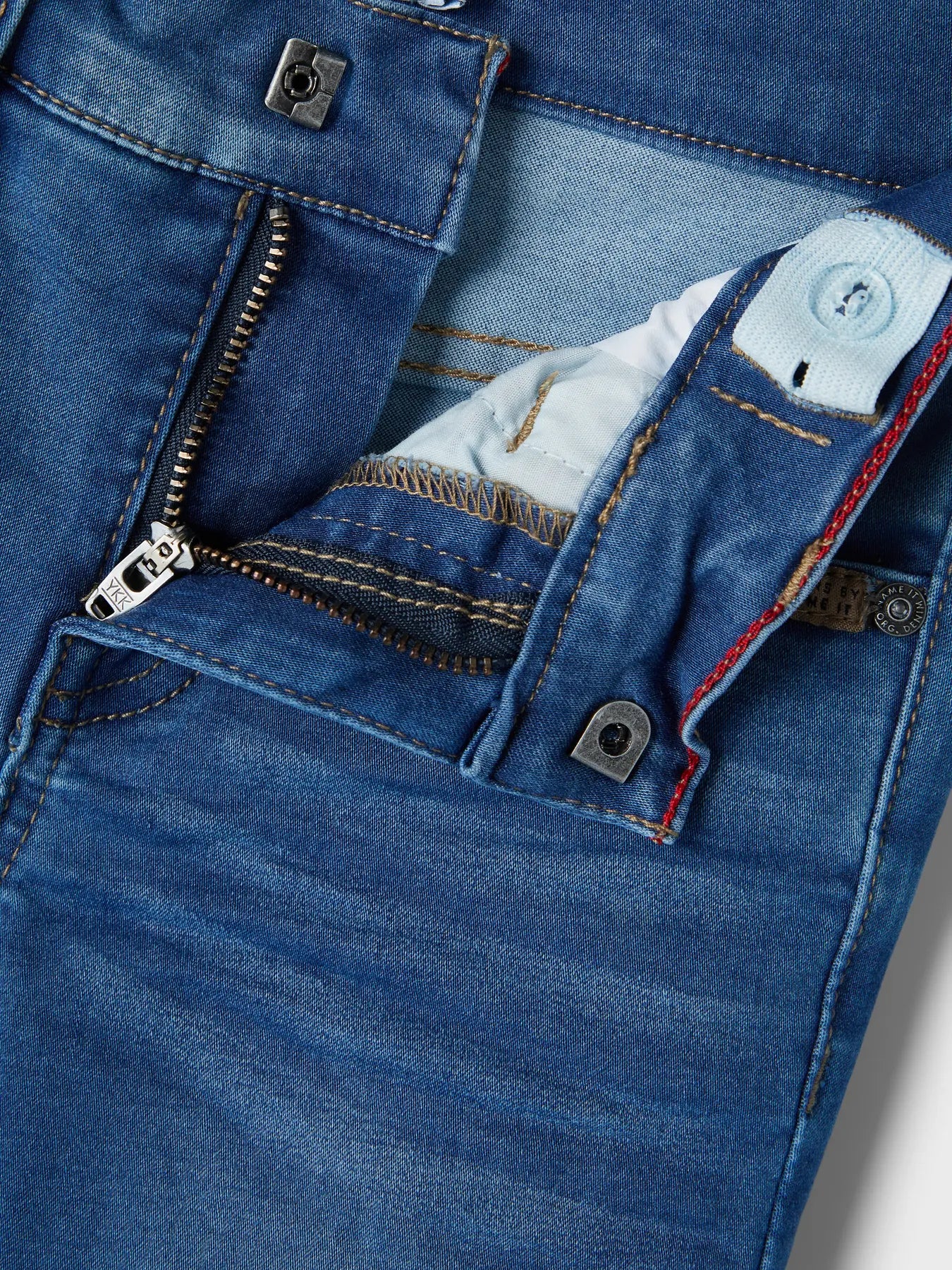 Close-up of blue denim jeans with a focus on the zipper and stitching details.