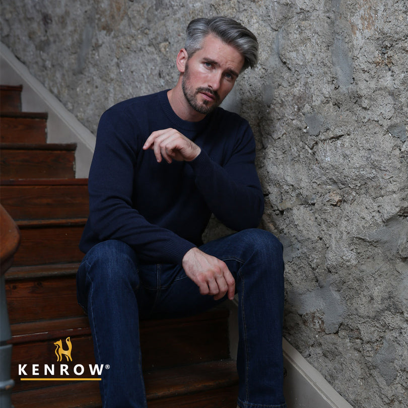 Man wearing a navy melange colour crew neck jumper sitting on a stairs