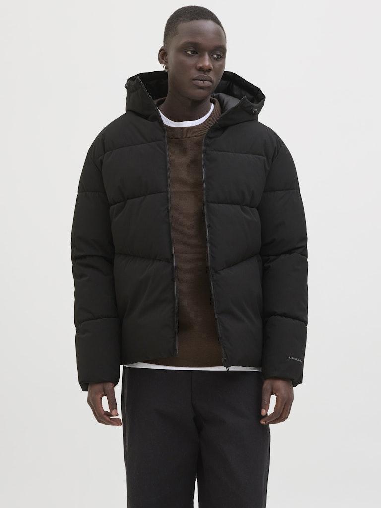 Person wearing a black puffer jacket on a white background