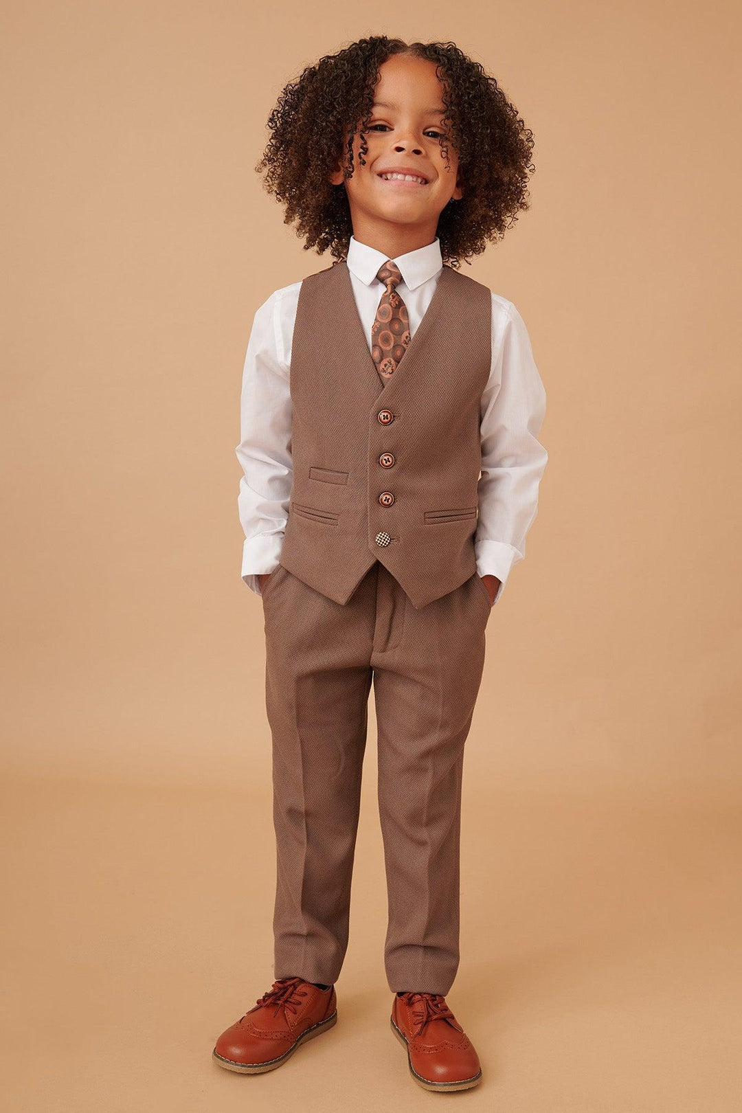 Child wearing a brown suit with a tie on a beige background