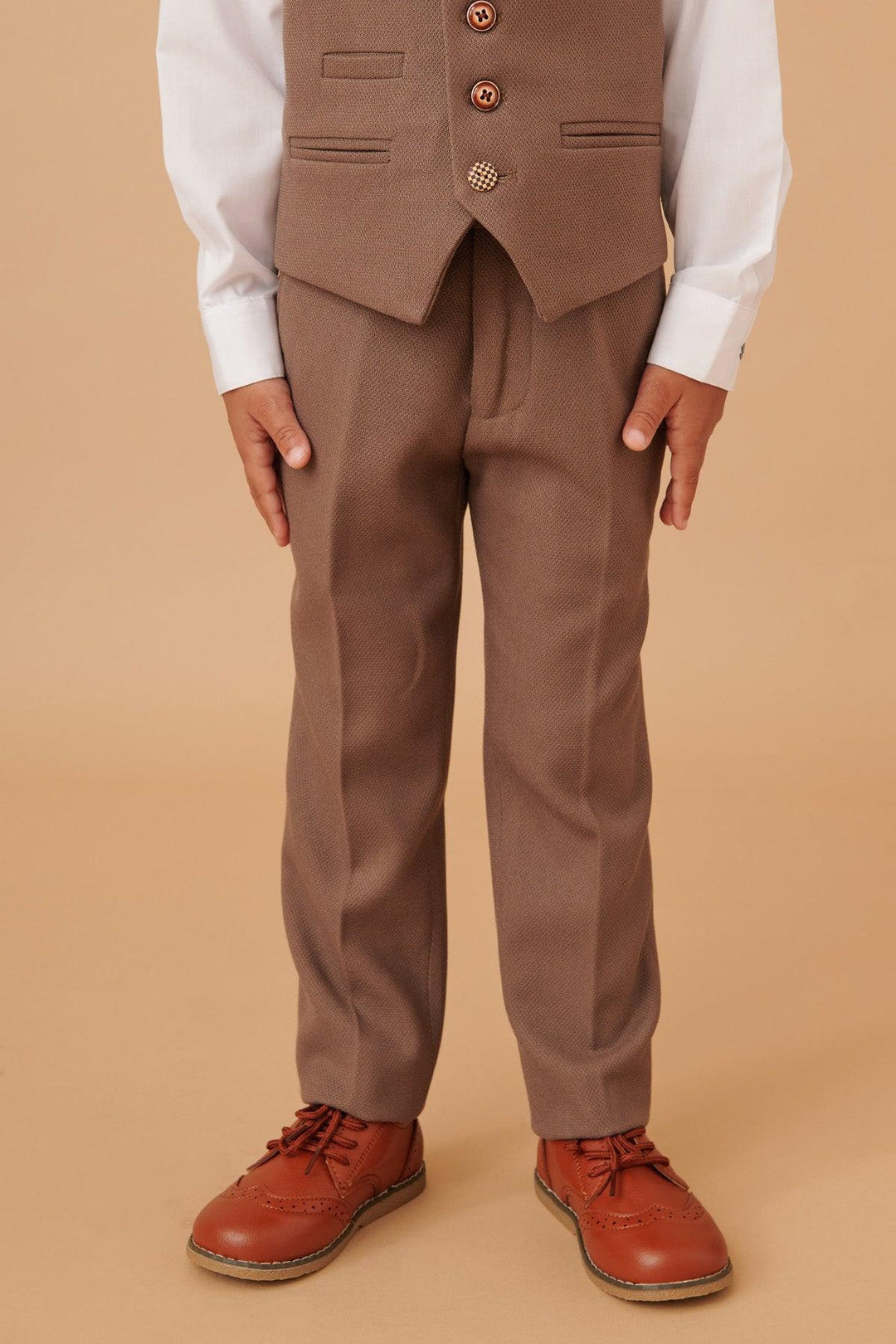 Person wearing a brown suit with a white shirt and red shoes on a beige background