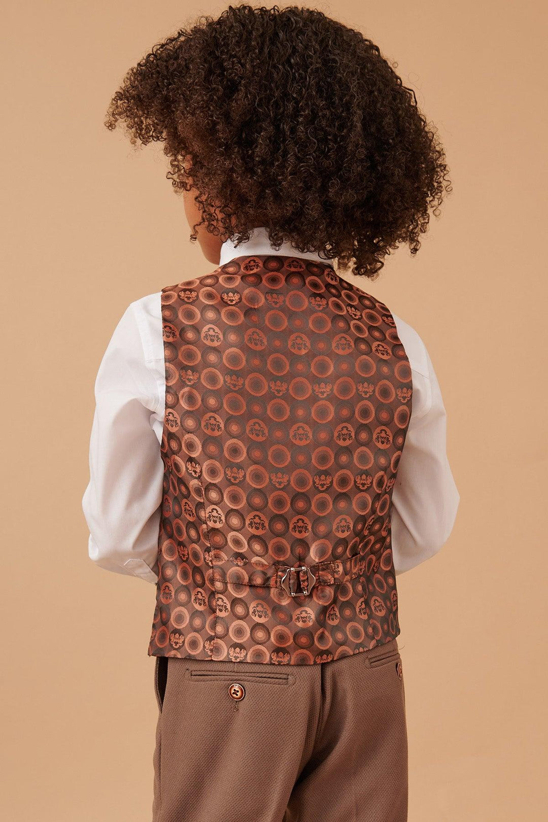 Person wearing a patterned vest over a white shirt on a beige background