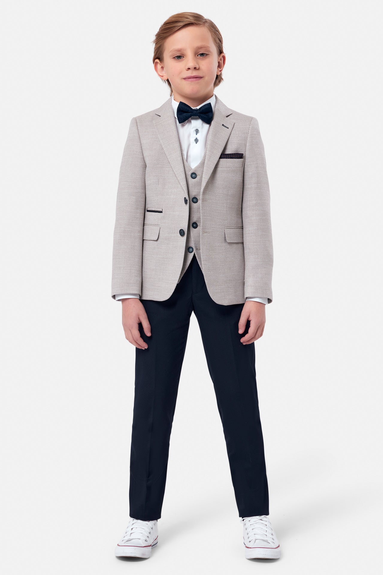 Boy wearing a beige textured blazer with beige waist coat and navy pants