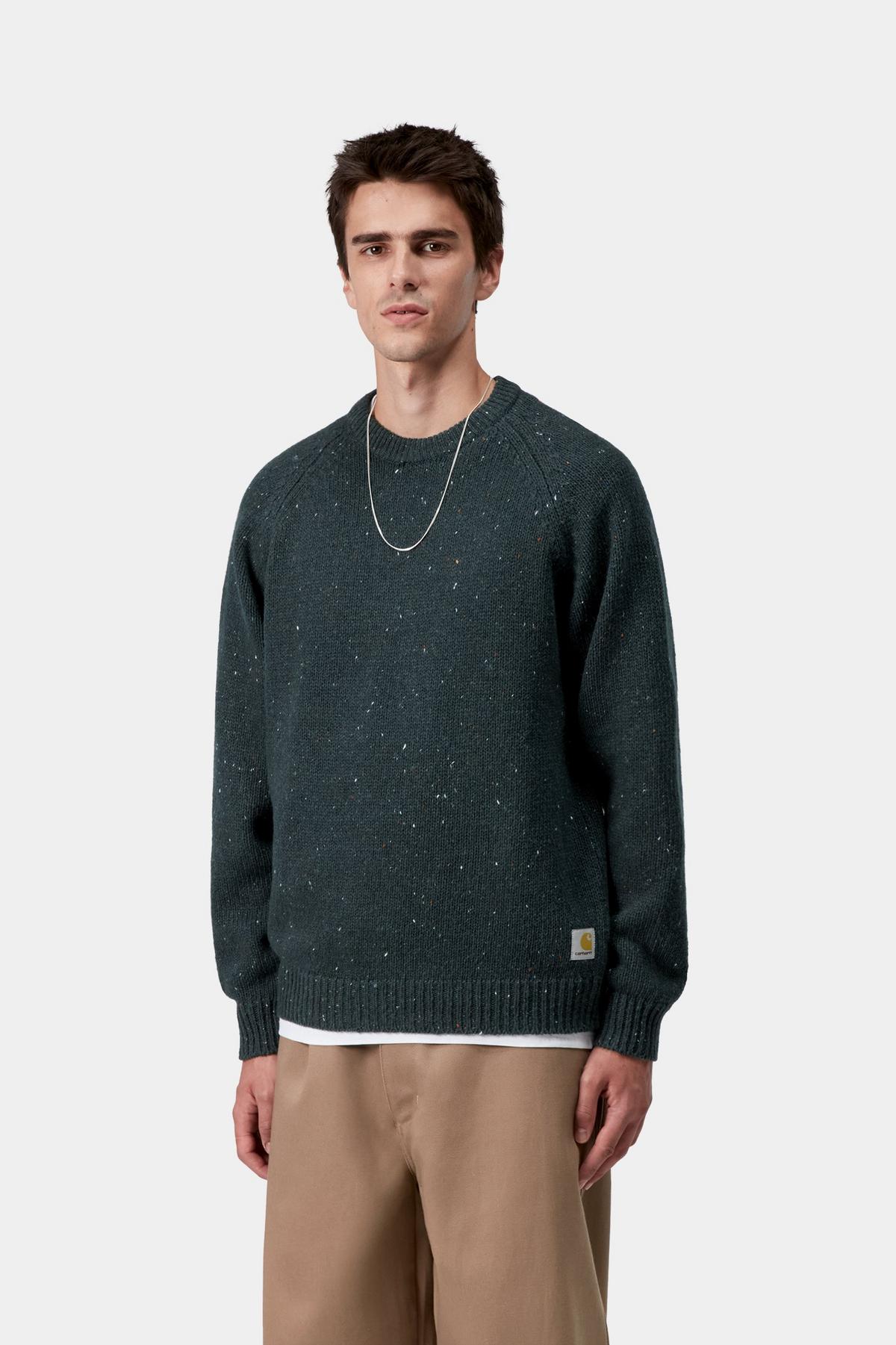 Man wearing a dark green sweater and beige pants on a white background
