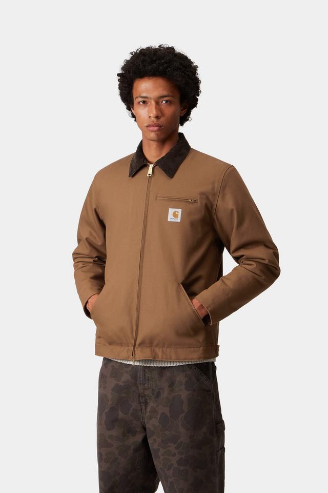 Man wearing a brown jacket with a visible brand logo on a white background