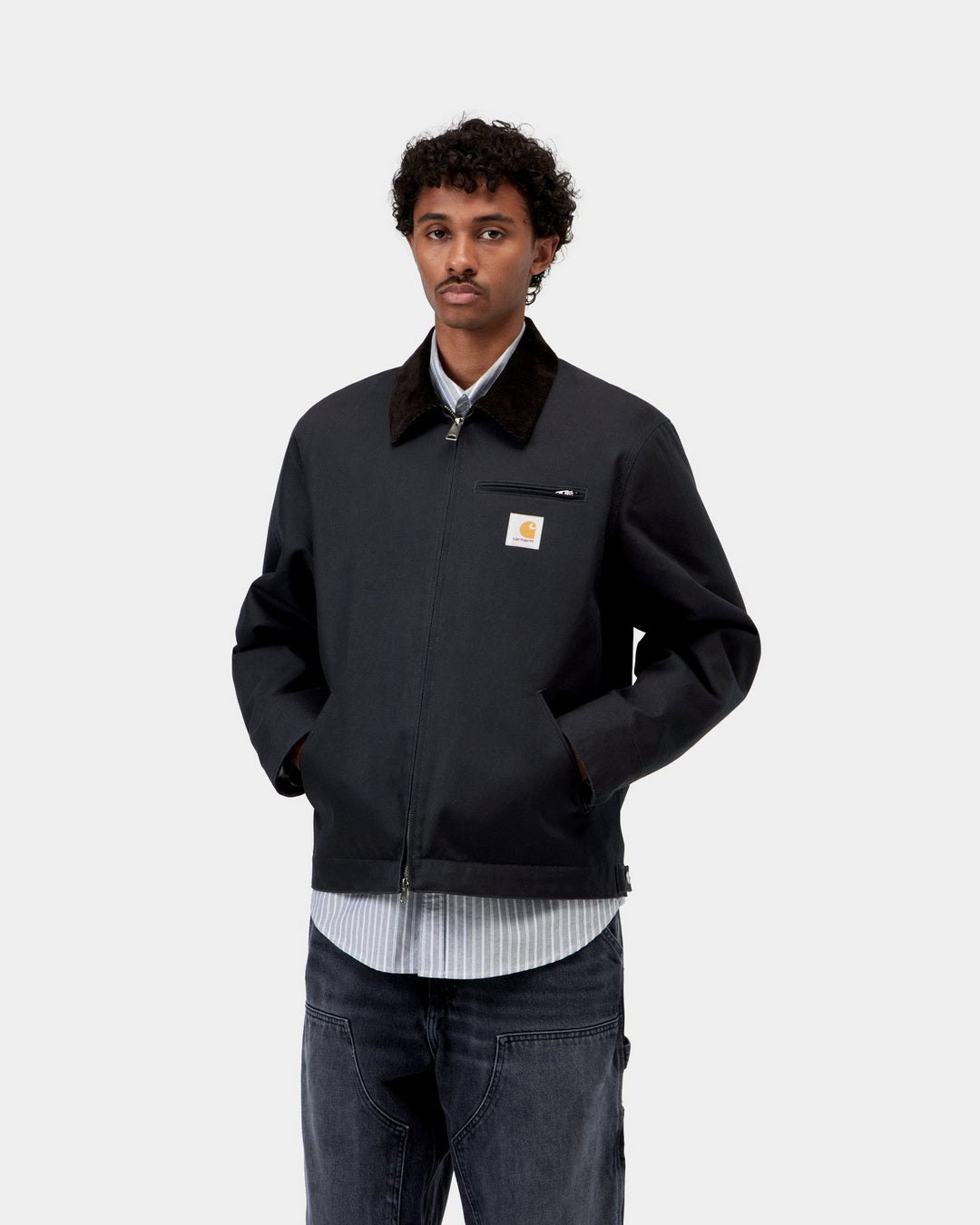 Carhartt WIP Detroit Jacket in Dark Navy / Black, front view on model with corduroy collar and chest zip pocket.