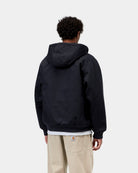 Back view of the Carhartt WIP Active Jacket in Dark Navy worn by a model, showing the hood, ribbed cuffs and hem, and a white layer peeking out beneath.