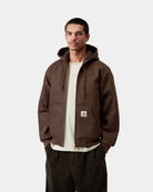 Carhartt WIP Active Jacket in Tobacco worn by a model, front view with hood up, gold-tone zip, kangaroo pockets, and square Carhartt logo patch on the left pocket.