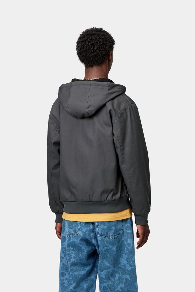 Person wearing a gray hooded jacket and blue patterned pants on a white background