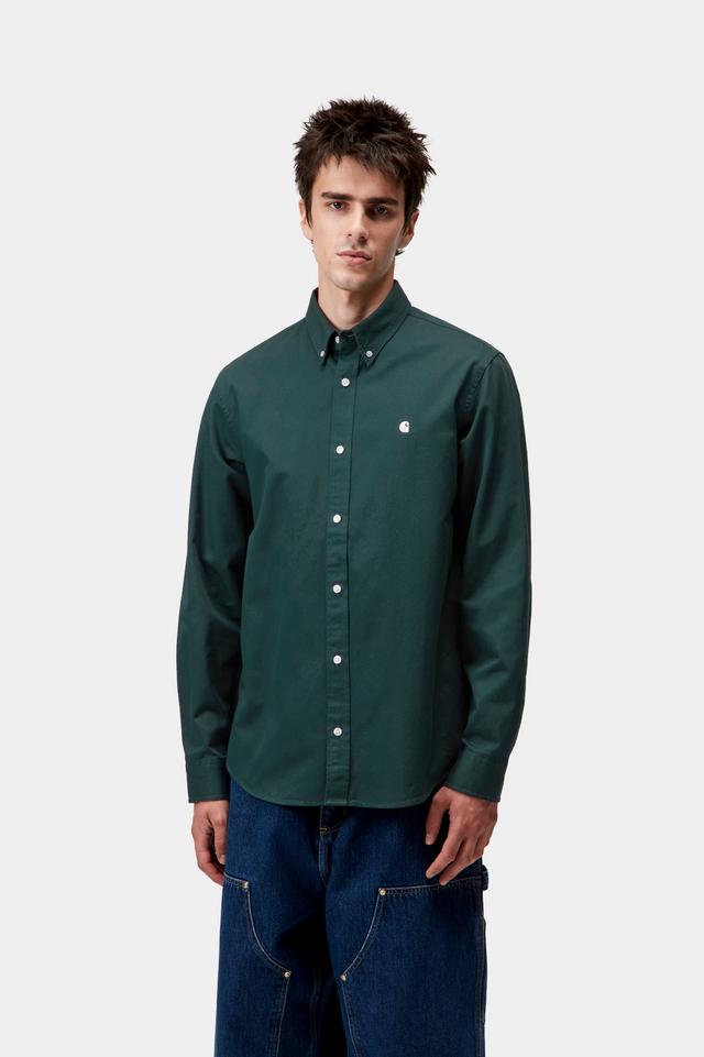 Man wearing a green button-up shirt and blue jeans on a white background
