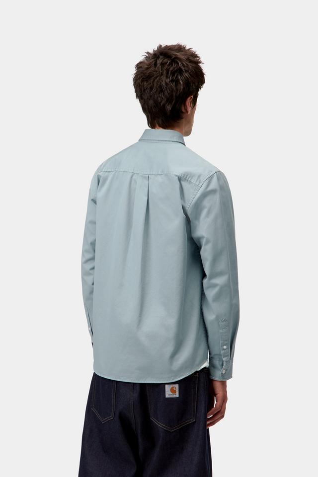 Person wearing a light blue shirt and dark pants on a white background