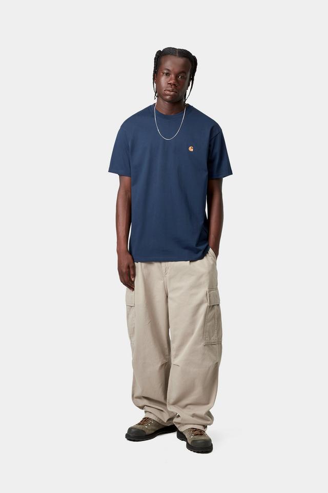 Man wearing a short sleeve Chase T-Shirt in jupiter / gold and beige baggy cargo pants