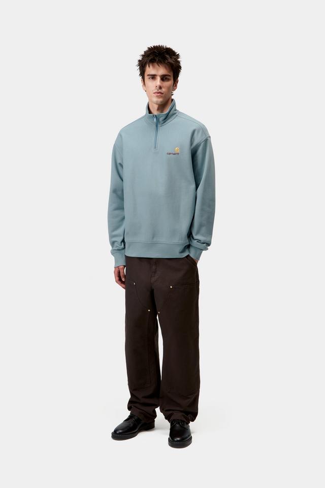 Man wearing a light blue pullover with a logo on a white background