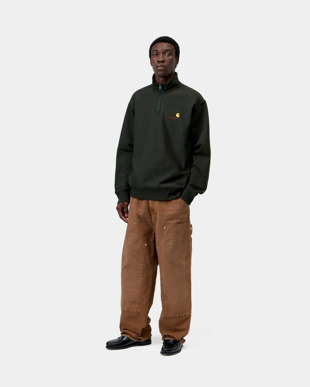 Carhartt WIP Half Zip American Script Sweatshirt in Raven, front view, worn by model with half-zip high neck and small chest logo.