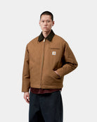 Carhartt WIP OG Detroit Jacket in WIP H Brown / Tobacco, front view on model with dark corduroy collar, zip front, chest pocket and logo patch.