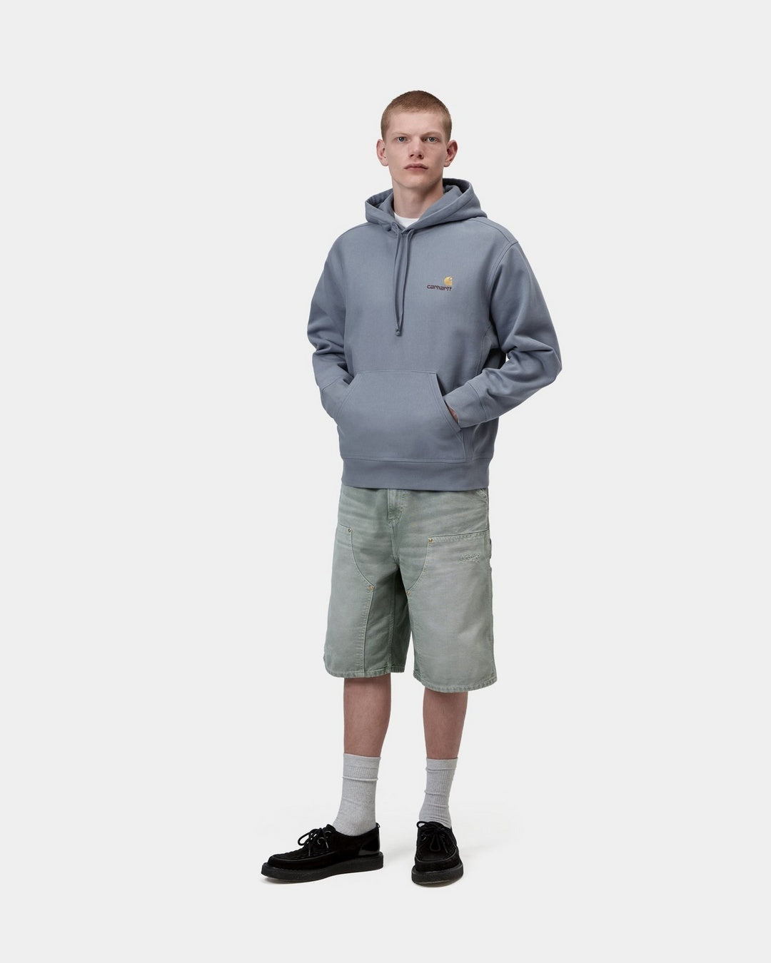 Carhartt WIP Hooded American Script Sweatshirt in Shady Blue, worn on a model with kangaroo pocket and front logo embroidery.