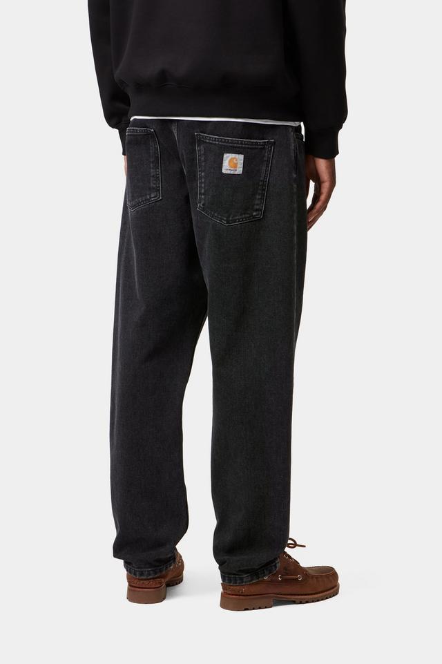Man wearing black stone wash Newel jean pants and a black Carhartt sweatshirt from behind