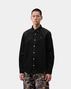 Carhartt WIP L/S Madison Cord Shirt in Soot, front view, buttoned-up corduroy shirt with button-down collar and chest logo, shown on model.