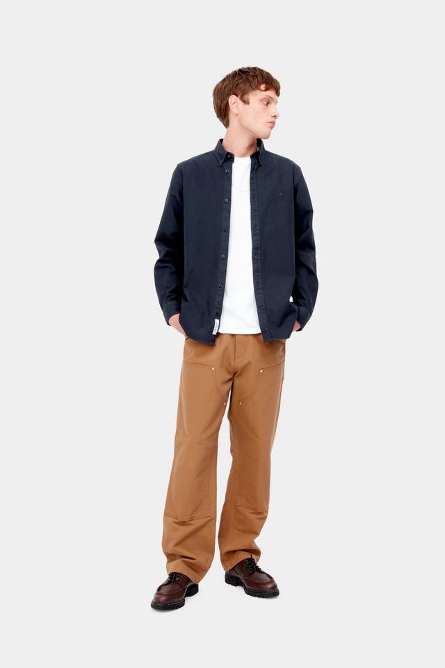 Man wearing a navy jacket, white shirt, and brown pants on a white background