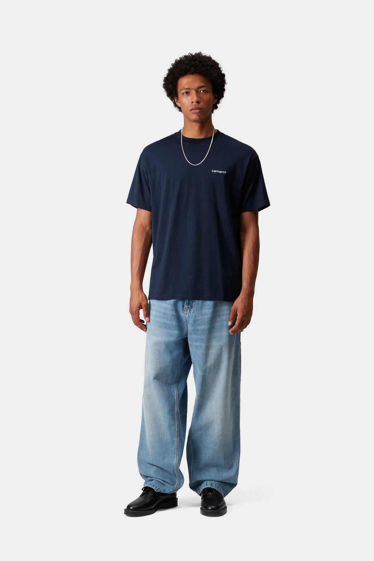 Person wearing a navy t-shirt and light blue jeans on a white background