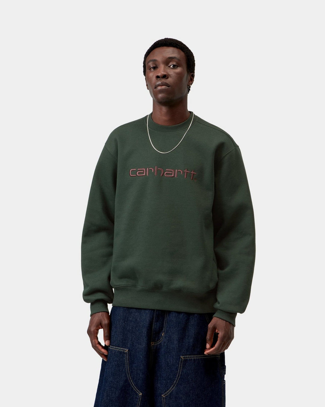 Carhartt WIP sweatshirt in Dark Scarab with Palisander embroidered logo on the chest, shown from the front, shown on model.