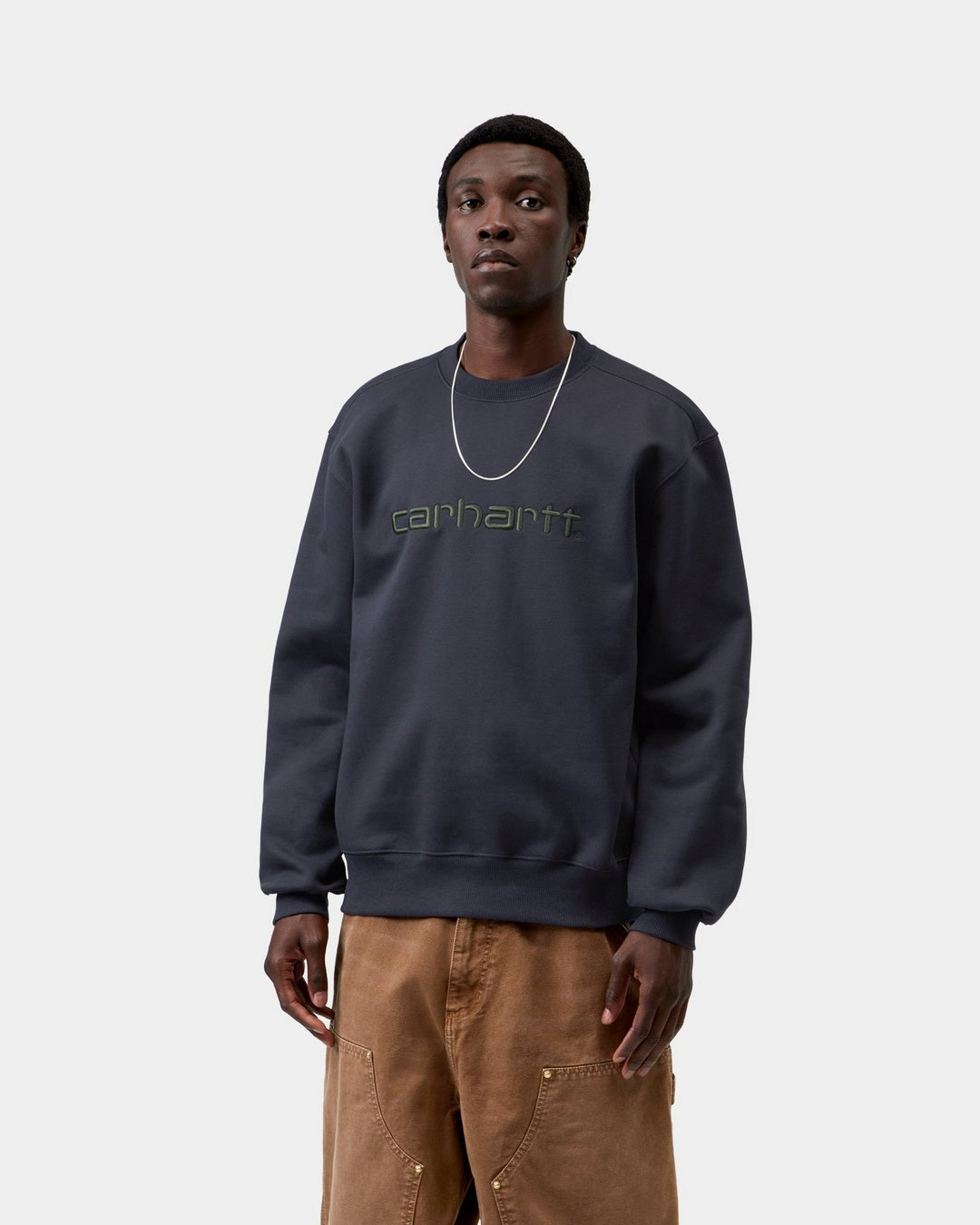 Carhartt WIP sweatshirt in Dark Navy / Dark Scarab with embroidered logo on the chest, shown on model from the front.