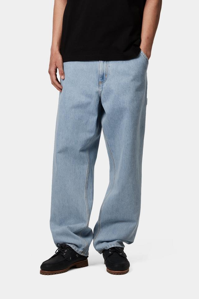 Person wearing light blue jeans and black shoes on a white background