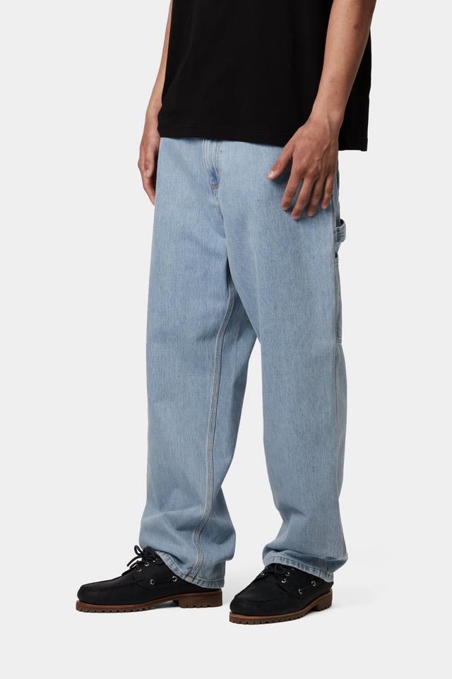 Person wearing light blue jeans and black shoes on a white background