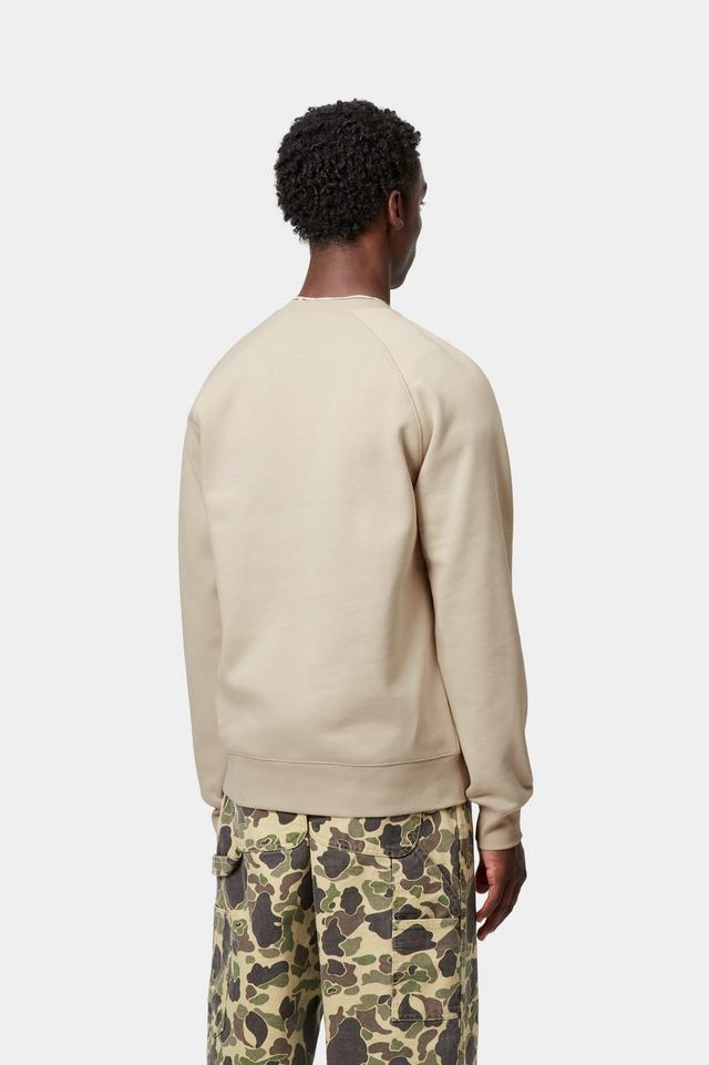 Person wearing a beige sweater and camouflage pants on a white background